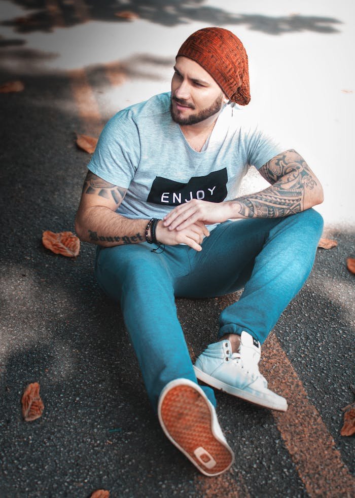 The Art of Drawing Readers In: Your attractive post title goes here A stylish man with tattoos sits casually on a street covered in autumn leaves.