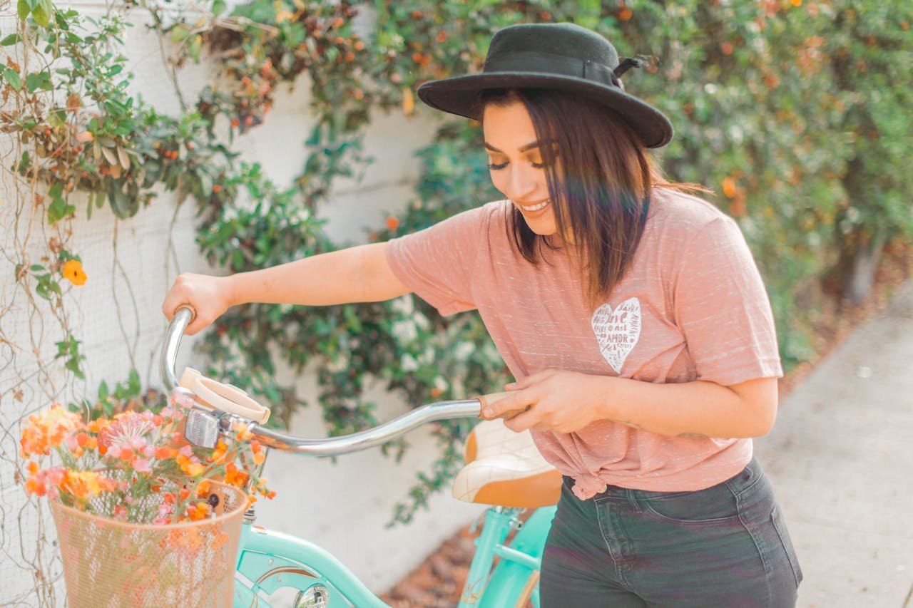 Cheerful young woman wearing a hat enjoys a sunny day with a vintage bike